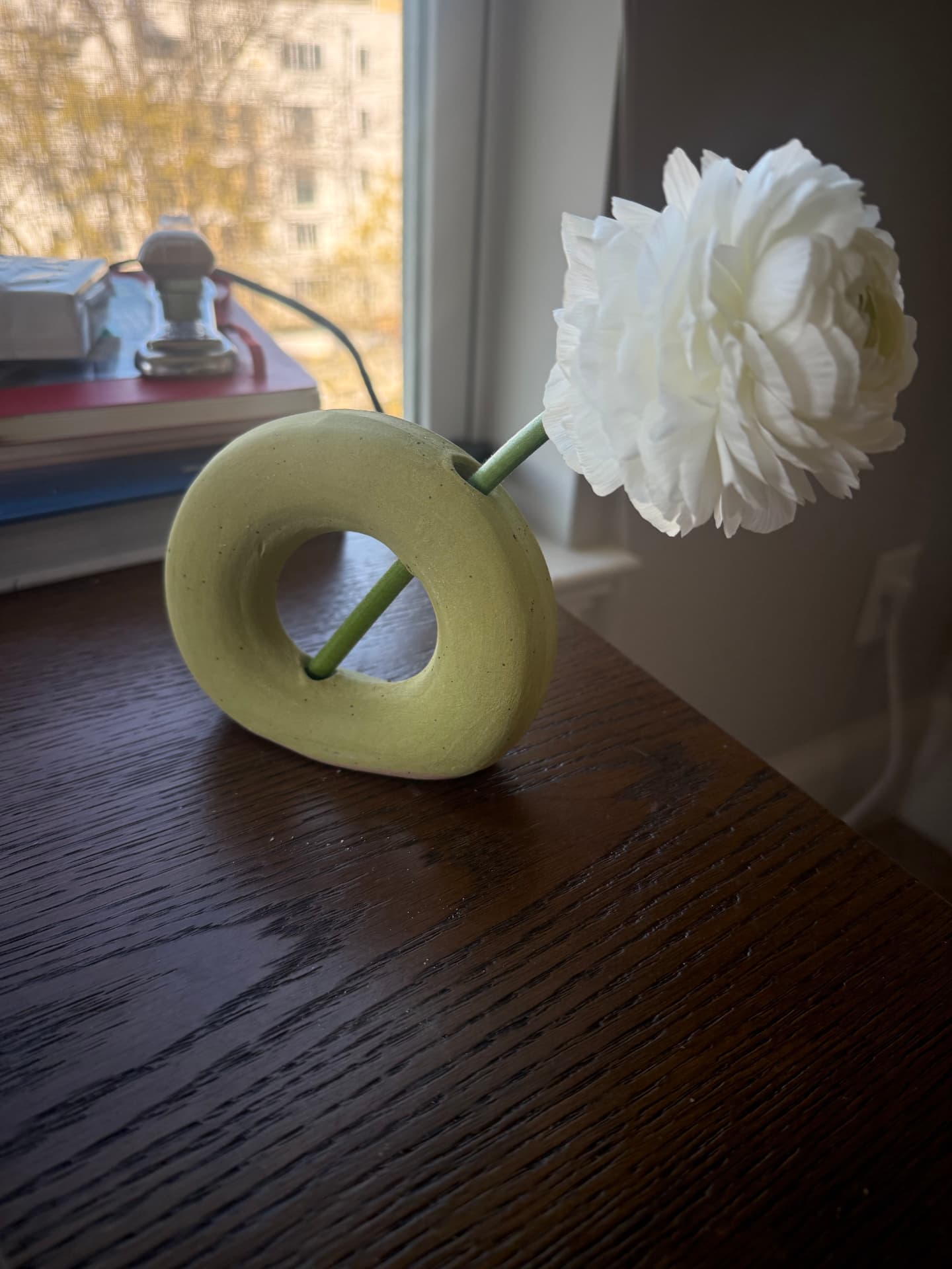 Pale green ring-shaped bud vase holding a single white flower